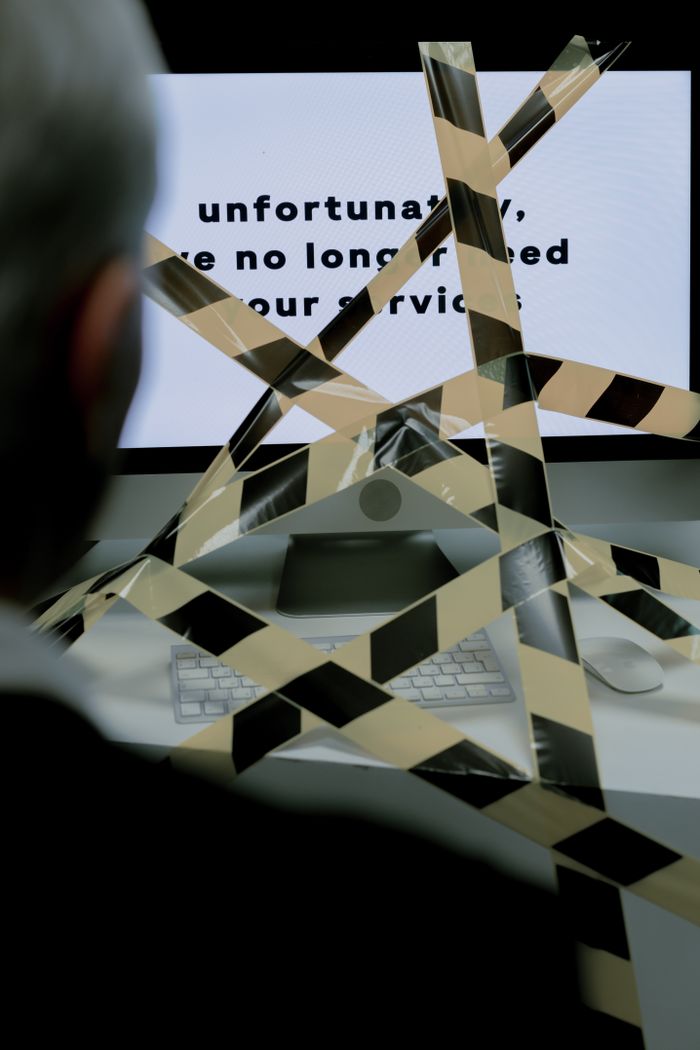 about-us-02 A man views a rejection message on a computer screen blocked by caution tape, symbolizing unemployment.
